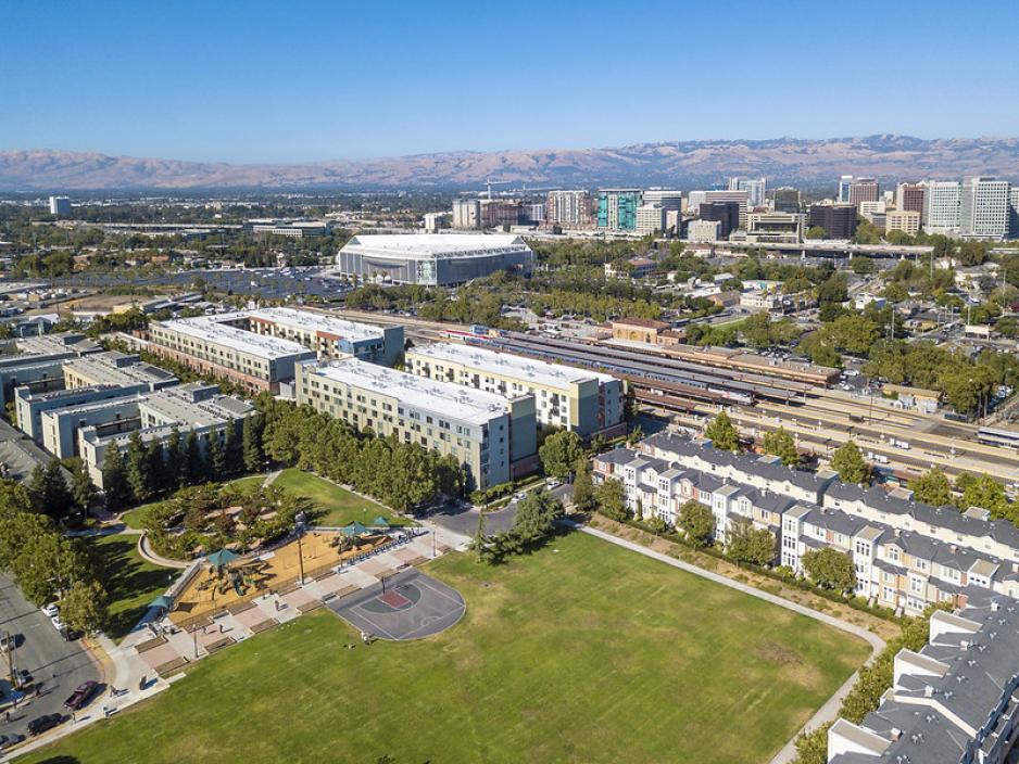 A photo of mixed-use building near a park and a transit rail station.